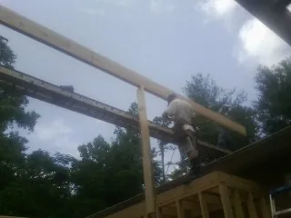Carpenter setting a ridge beam over a new addition frame — Ice Dam Removal by Roofing Brothers in Saint Catharine