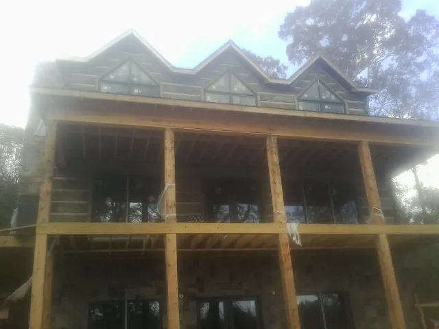 Dormers and porch framing on a large log home under construction — Roof Coating work by our crew in Saint Catharine