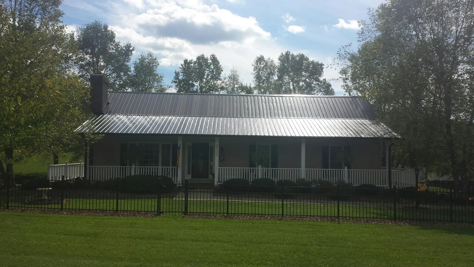 Gray metal roof on a brick ranch with a full width front porch — Gutter Guard Installation work by our crew in Saint Catharine