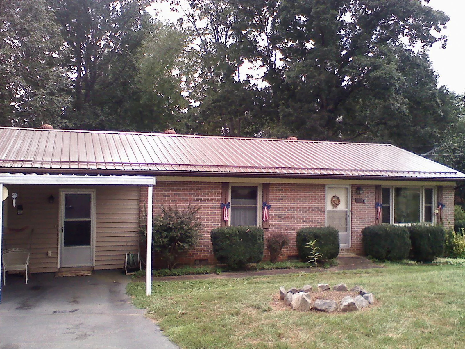 Bronze metal roof and carport on a brick ranch home — Roof Repair work by our crew in Saint Catharine